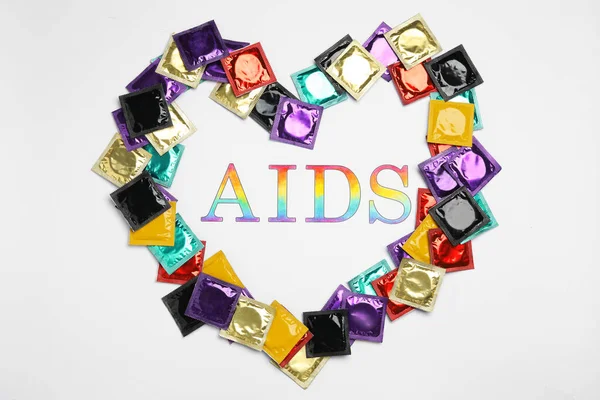 Frame made of colorful condoms with word AIDS inside on white background, top view. Safe sex — Stock Photo, Image