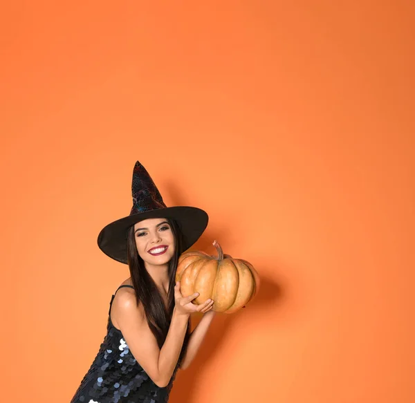 Mooie vrouw in heks kostuum met pompoen voor Halloween feest op gele achtergrond, ruimte voor tekst — Stockfoto