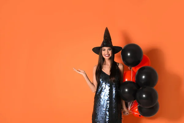 Bella donna che indossa costume da strega con palloncini per la festa di Halloween su sfondo giallo, spazio per il testo — Foto Stock