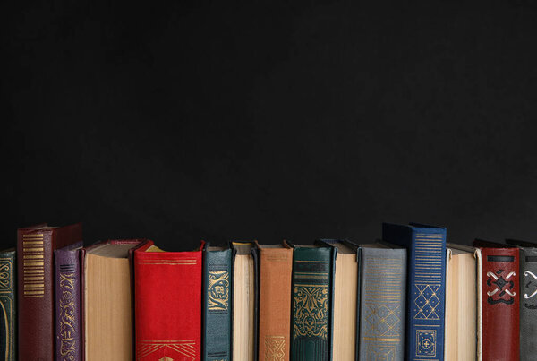 Stack of hardcover books on black background. Space for text