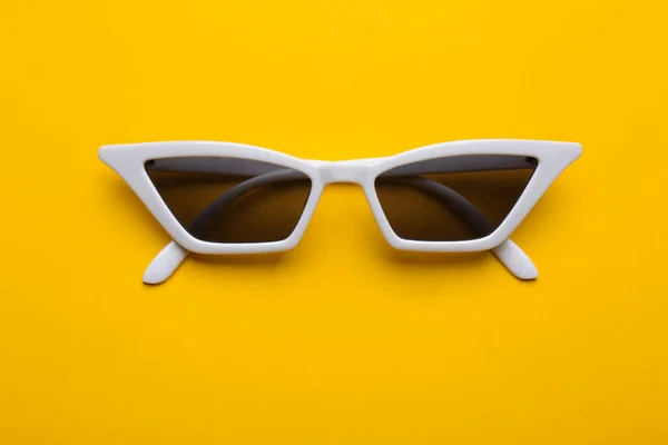 Стильные солнечные очки на желтом фоне, вид сверху. Модный аксессуар — стоковое фото