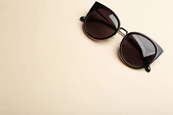 Elegantes gafas de sol sobre fondo beige, vista superior con espacio para texto. Accesorio de moda —  Fotos de Stock