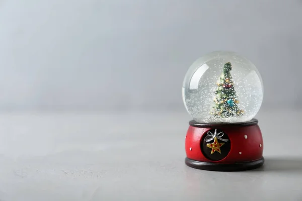 Sněhová koule s vánočním stromečkem na šedém stole, prostor pro text — Stock fotografie