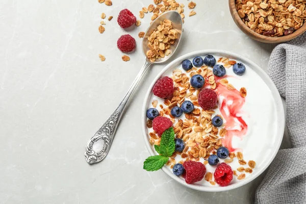 Здорова домашня гранола з йогуртом та ягодами, подається на світло-сірому столі, плоска. Простір для тексту — стокове фото