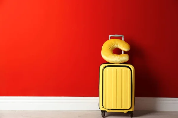 Maleta amarilla y almohada de viaje cerca de la pared roja, espacio para texto — Foto de Stock