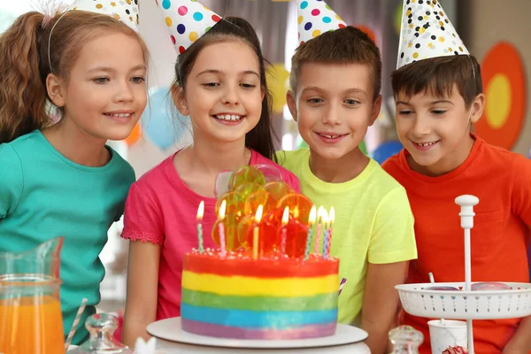 Niños cerca de la torta con velas en la fiesta de cumpleaños en interiores —  Fotos de Stock