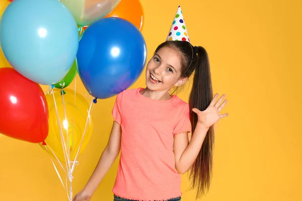 Gelukkig meisje met ballonnen op gele achtergrond. Verjaardagsfeest — Stockfoto