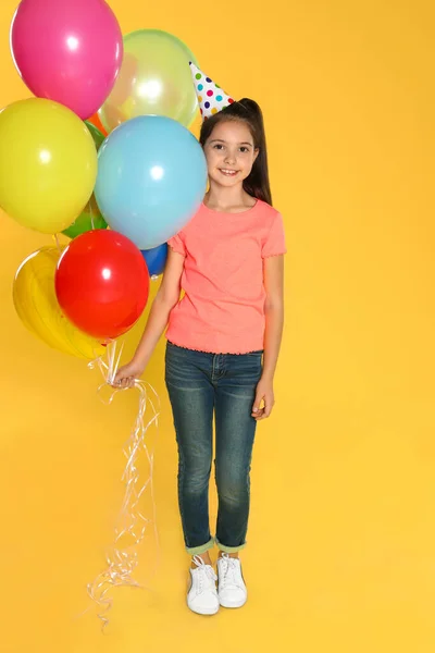 Menina feliz com balões no fundo amarelo. Celebração de aniversário — Fotografia de Stock