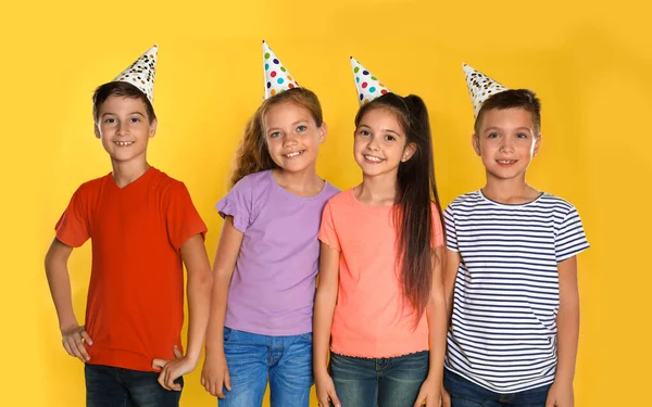 Boldog gyerekek parti sapkában sárga háttérben. Születésnapi ünneplés — Stock Fotó