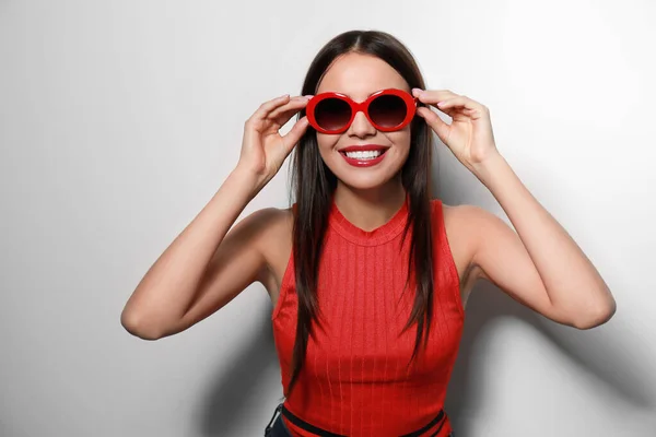 Mulher bonita em óculos de sol elegantes no fundo claro — Fotografia de Stock