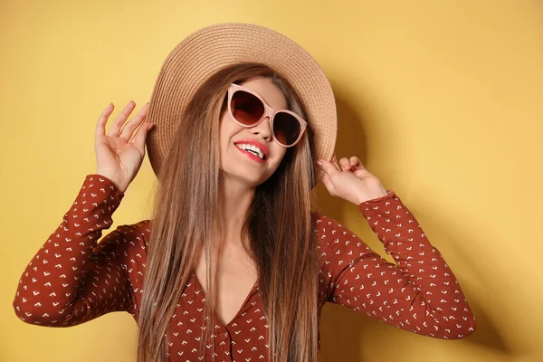 Giovane donna indossa occhiali da sole alla moda e cappello su sfondo giallo — Foto Stock