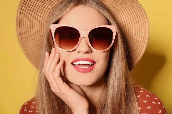 Young woman wearing stylish sunglasses and hat on yellow background — Stock Photo, Image