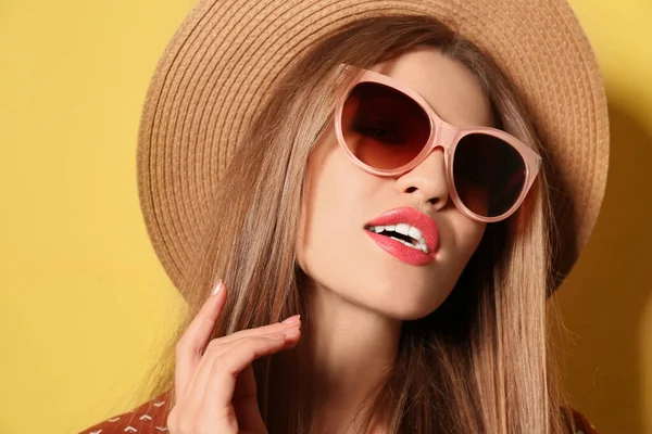 Young woman wearing stylish sunglasses and hat on yellow background — Stock Photo, Image