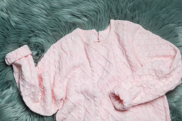 Pink knitted sweater on green fur rug, flat lay — Stock Photo, Image