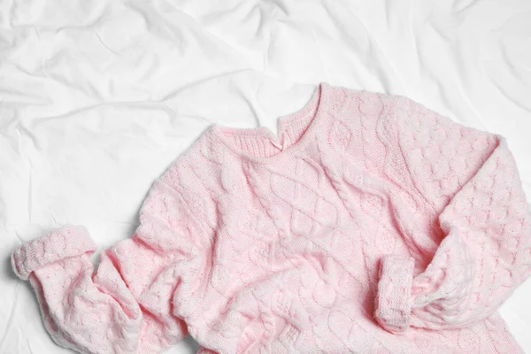 Pink knitted sweater on white fabric, flat lay — Stock Photo, Image