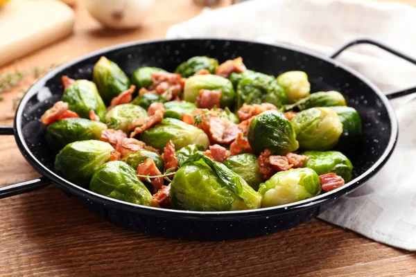 Lekker geroosterde spruitjes met spek op houten tafel, close-up — Stockfoto