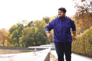 Parkta koşan şişman genç bir adam. Fitness yaşam tarzı