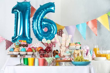16. yaş günü partisi için mavi balonlarla süslenmiş tatlı masası.