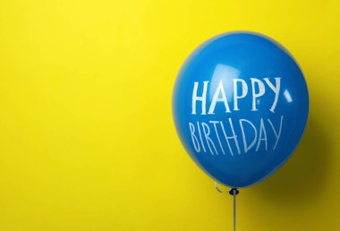 Sarı arkaplanda mutlu yıllar yazılı mavi balon, metin için boşluk