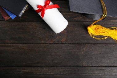 Mezuniyet şapkası ve öğrenci diplomasıyla siyah ahşap masa üzerinde düz kompozisyon, metin için boşluk