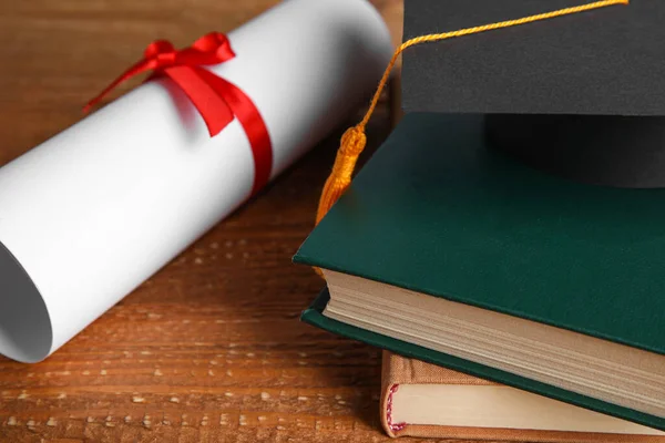 Καπέλο αποφοίτησης, βιβλία και δίπλωμα φοιτητή σε ξύλινο τραπέζι, κοντινό πλάνο — Φωτογραφία Αρχείου