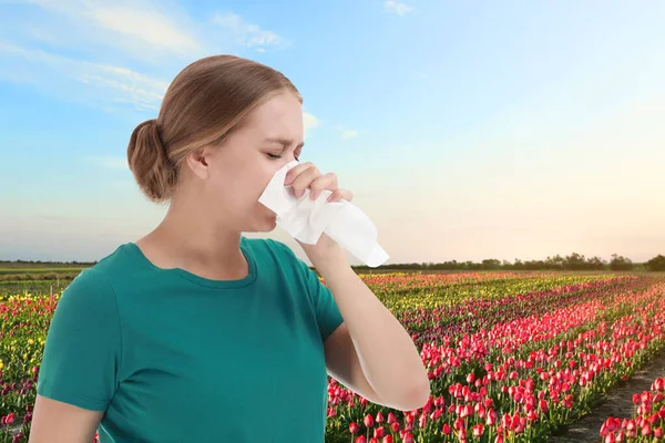 Ung kvinna som lider av allergi och blommande fält på bakgrunden — Stockfoto