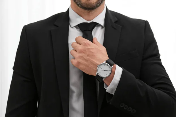 Businessman adjusting necktie on light background, closeup — Stock Photo, Image