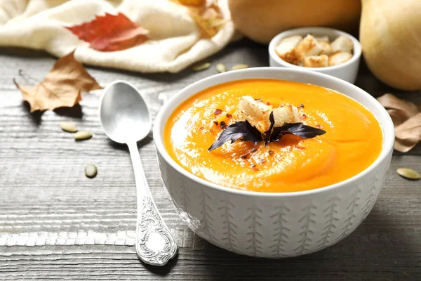 Delicious pumpkin soup in bowl on wooden table — Stock Photo, Image