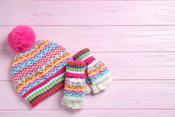 Warm knitted hat and mittens on pink wooden background, flat lay. Space for text — Stock Photo, Image