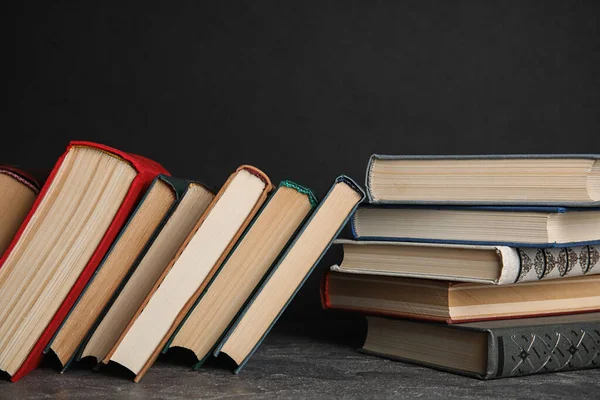 Montón de libros de tapa dura sobre mesa de piedra gris sobre fondo negro — Foto de Stock