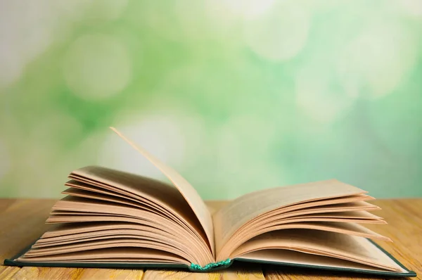 Nyitott könyv fa asztal homályos zöld háttér. A szöveg helye — Stock Fotó