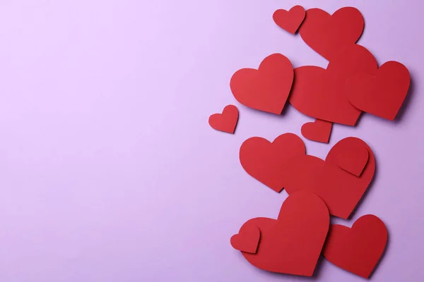 Rode papieren hartjes op violette achtergrond, plat gelegd. Ruimte voor tekst — Stockfoto