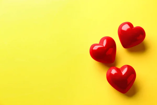 Corazones rojos sobre fondo amarillo, posición plana. Espacio para texto — Foto de Stock