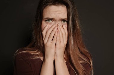 Karanlık arka planda üzgün genç bir kadının portresi