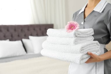 Otel odasında temiz havlu yığını olan oda hizmetçisi, yakın çekim. Metin için alan