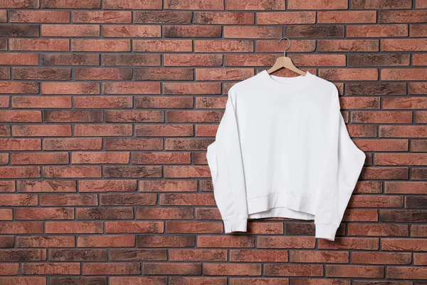 Appendiabiti con nuovo maglione su muro di mattoni, modellare per il design — Foto Stock