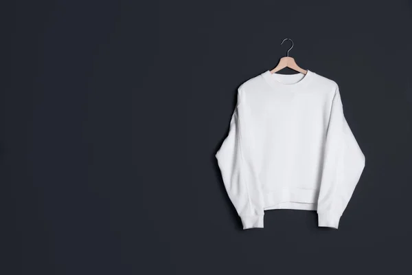 Hanger met nieuwe trui aan donkere muur, model voor ontwerp — Stockfoto