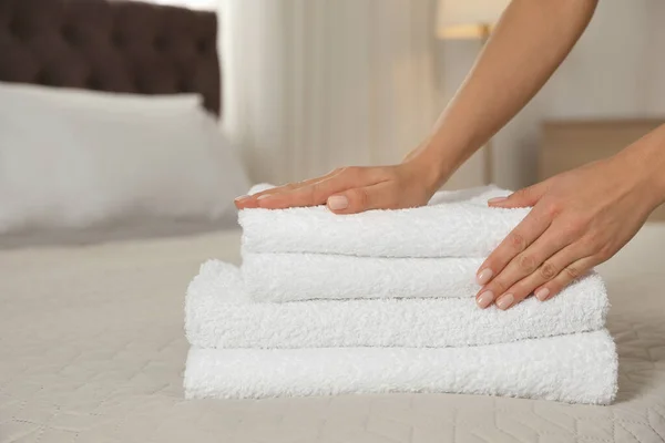 Chambermaid putting fresh towels on bed in hotel room, closeup. Space for text — Stock Photo, Image