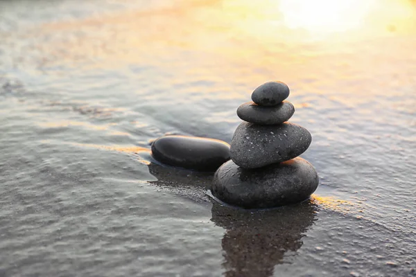 Pedras escuras na areia perto do mar ao pôr do sol, espaço para texto. Conceito Zen — Fotografia de Stock