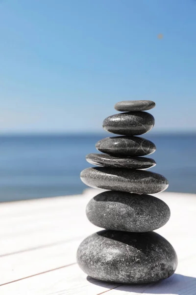 Stack of stones on wooden pier near sea, space for text. Zen concept — Stock Photo, Image