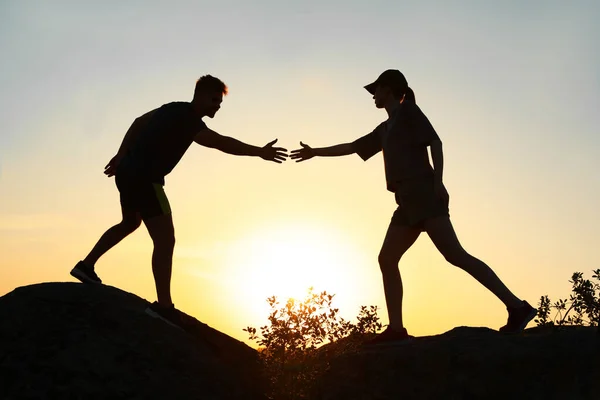 Wandelaar helpt vriend buitenshuis bij zonsondergang. Help en ondersteuning concept — Stockfoto