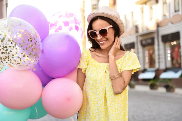 Красива молода жінка з кольоровими кульками на міській вулиці — стокове фото