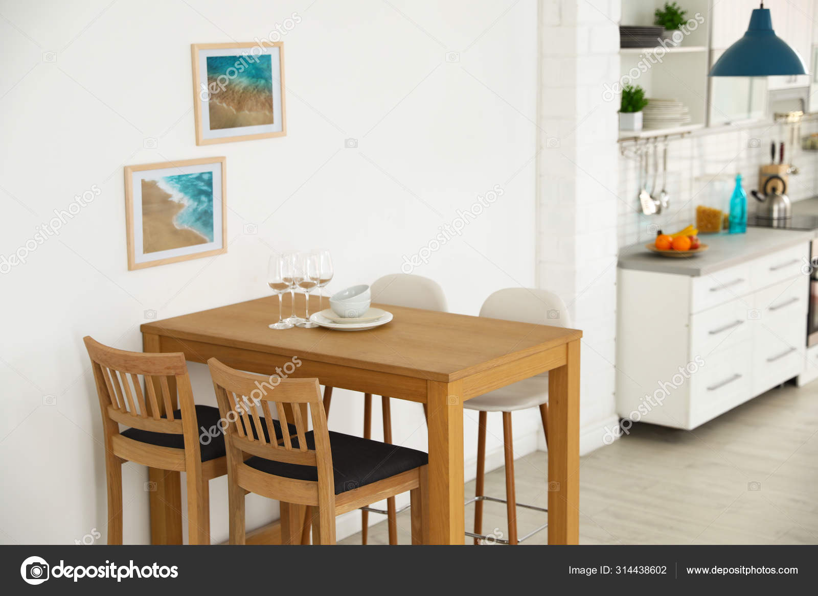 Stylish Kitchen Interior With Dining Table And Bar Stools Near White Wall Stock Photo