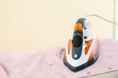 Bej arka planda modern ütü ve tişörtü olan tahta, yazı için yer. Çamaşır günü