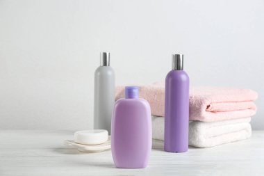 Temiz havlular ve tuvalet malzemeleri beyaz ahşap masada.