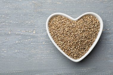 Gri ahşap masadaki organik kenevir tohumları, üst manzara. Metin için boşluk