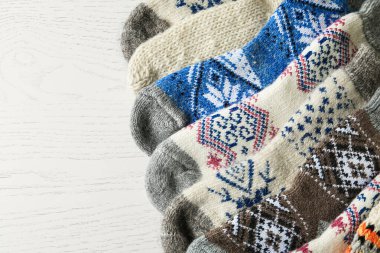 Beyaz ahşap arka planda yumuşak örülmüş çoraplar, düz yatış. Kış giysileri