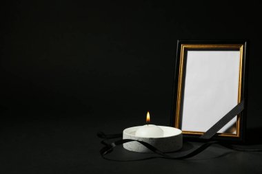 Siyah arka planda mum ve kurdeleli bir cenaze fotoğrafı çerçevesi. Tasarım için boşluk