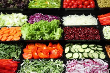 Arka planda farklı taze malzemeler bulunan salata barı.