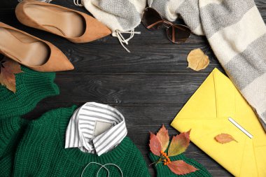 Düz kompozisyon, kalın giysiler ve siyah ahşap zemin üzerinde sonbahar yaprakları, metin için boşluk